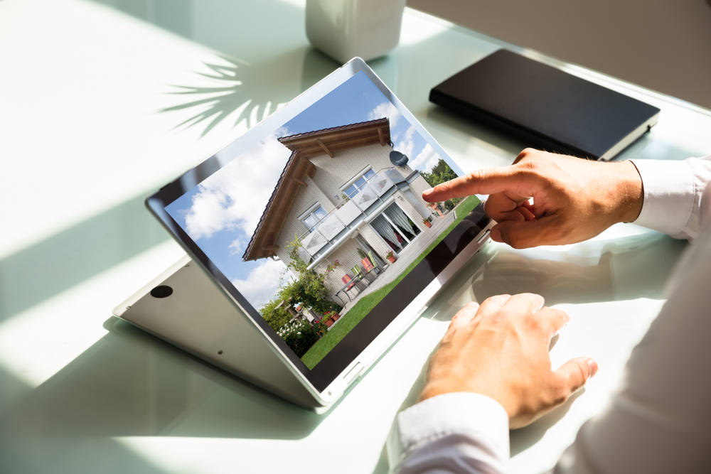 businessman's hand checking house on laptop
