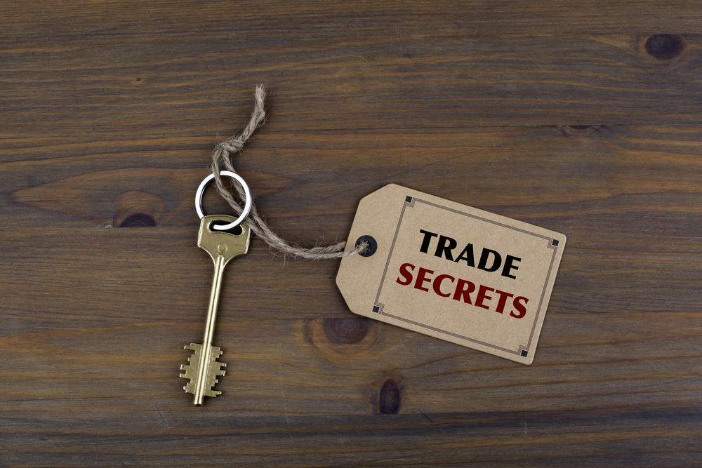 key and a note on a wooden table with text trade secrets